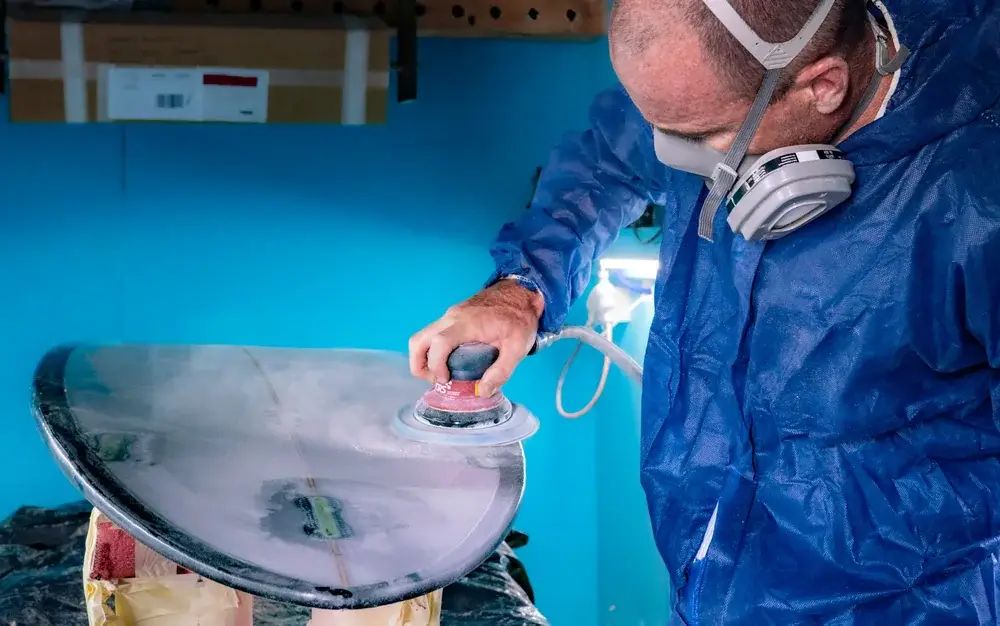Occupational hygienist in protective coveralls and respirator taking a workplace air sample