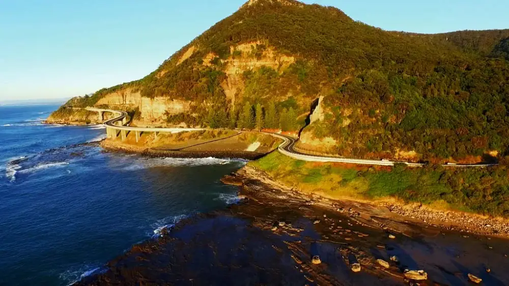 Aerial view of Sea Cliff Bridge curving out over the ocean along the Illawarra coastline, photographed from an Opterra drone